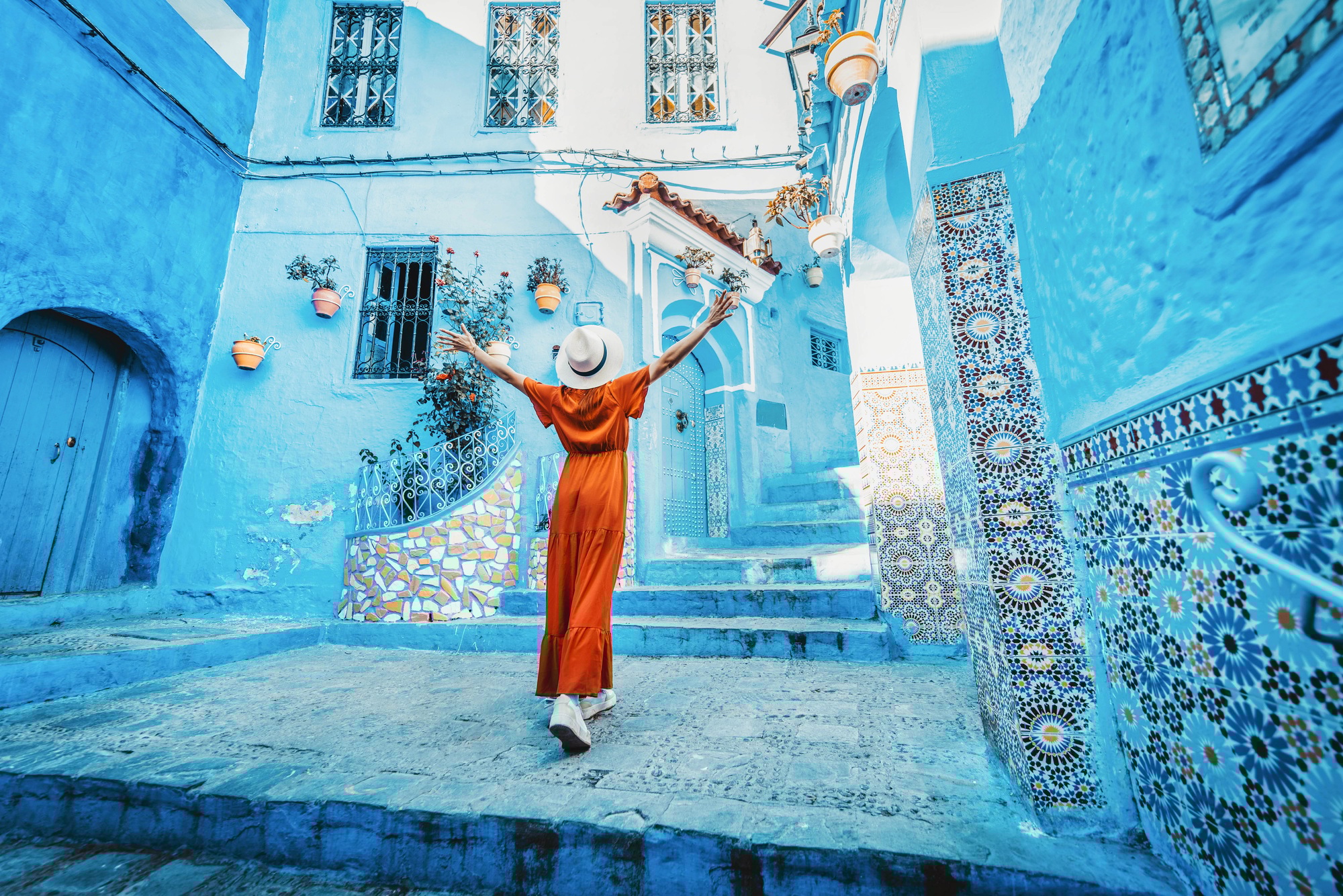 Young woman with red dress visiting the blue city Chefchaouen, Marocco