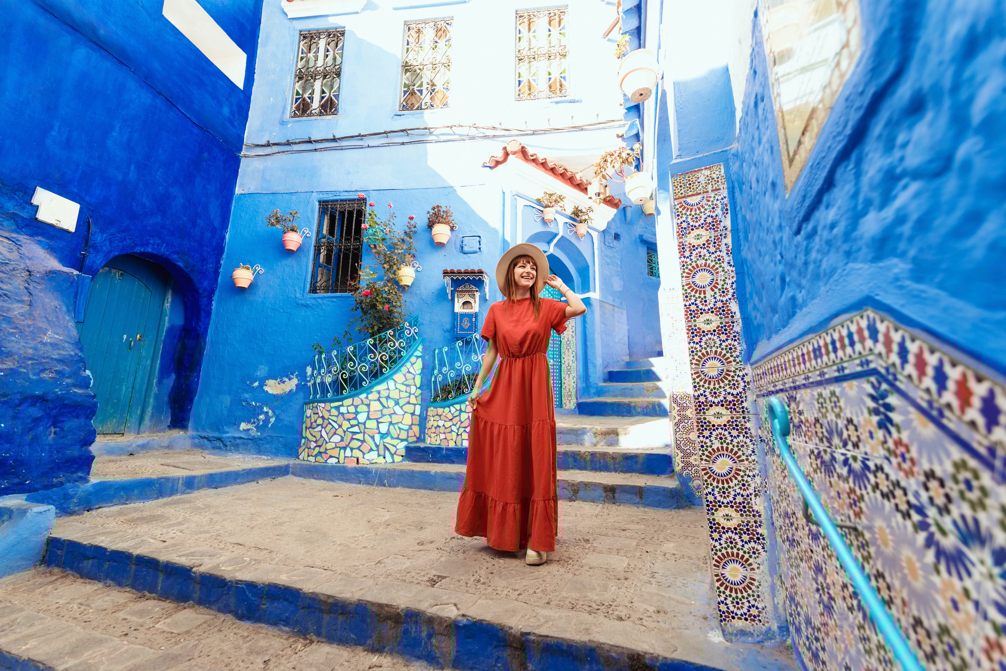 Young woman with red dress visiting the blue city Chefchaouen, Marocco